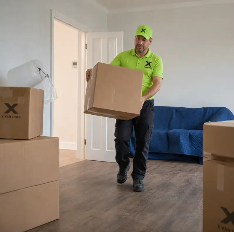 Mover carrying boxes into a new home