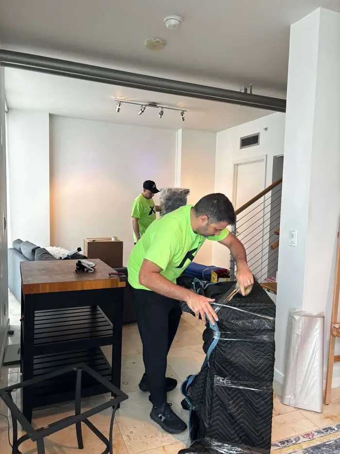 X Van Lines mover wrapping furniture in protective plastic